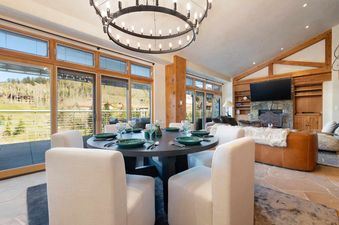 The dining area and living room of Peaks Penthouse 617 are furnished with modern decor and offer scenic views of the surrounding landscape.