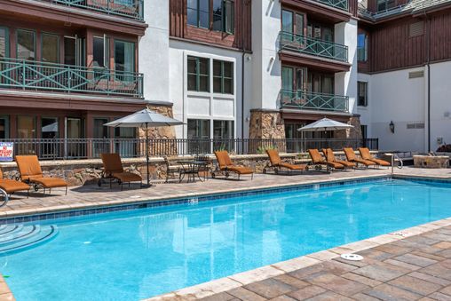 The outdoor pool area at Villa Montane features comfortable lounge chairs and umbrellas, all set against the backdrop of the resort's beautiful architecture.