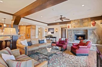 The Charter E340's elegant living room and kitchen feature a stone fireplace, leather sofas, red armchairs, a glass coffee table, and rich wooden cabinetry.