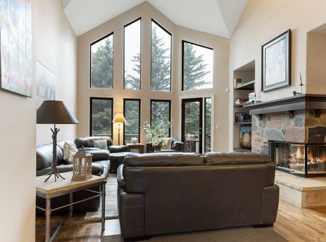 A living room with large windows and a fireplace.