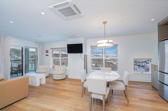 Living area inside Peaks Penthouse 334 with a dining table and chairs, armchairs, and an exterior view.