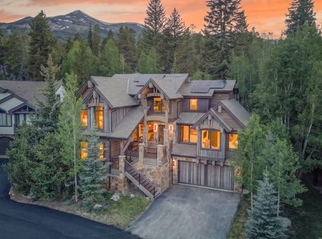 Moose Meadows Reserve, a luxury mountain home surrounded by pine trees under a warm sunset.