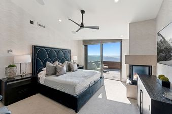 A luxurious bedroom featuring a king-sized bed, a fireplace, and a private balcony with stunning mountain views.