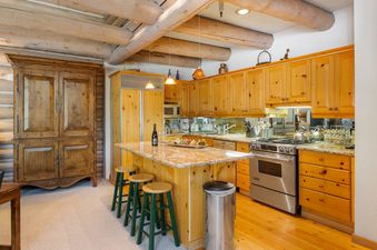 The kitchen in Pine Inn 3 features stainless steel appliances, granite countertops, wooden cabinets, and a breakfast bar with stools.