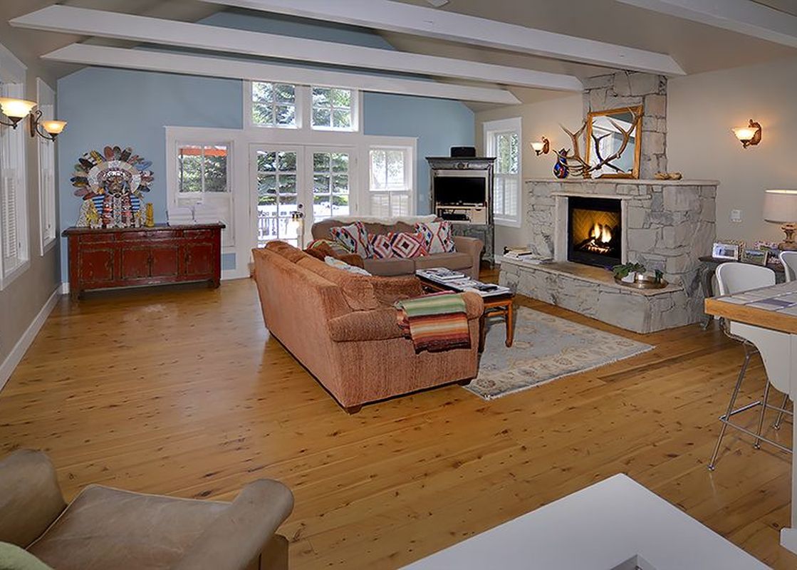 A spacious and inviting living room at The Bluebird Cottage, featuring rustic charm and a cozy fireplace, perfect for relaxation.