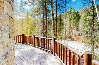 The wooden deck of Atkins Cabin has a railing and overlooks the forest.