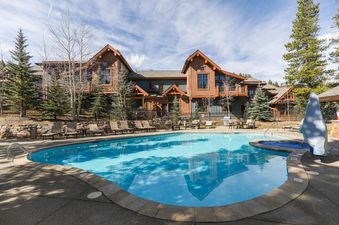 The Villa at Mountain Thunder features a large outdoor swimming pool with lounge chairs and hot tub, surrounded by a fence and mature trees, with the multi-story hotel building in the background.