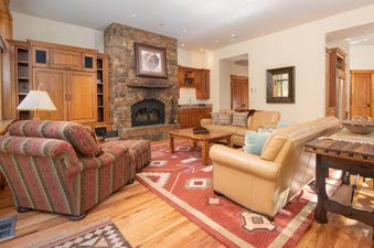 Cozy living room at the Granite Ridge Lodge 6 featuring a stone fireplace, leather sofas, and rustic wood accents.
