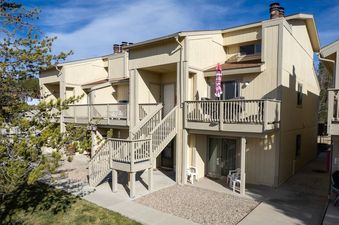 The exterior of Meadow Ridge 18 features multiple levels with balconies and outdoor spaces, surrounded by mature trees under a clear blue sky.