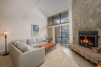 The Meadow Ridge 31 living room features a light gray sectional sofa, a wooden coffee table, and a fireplace with a stone surround.