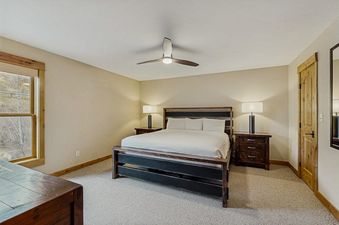 A master bedroom at Kutuk 211 with a king-size bed, rustic wood accents, and a large window offering mountain views.