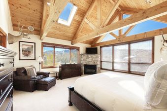 A bedroom with a king-sized bed, a fireplace, and views of the mountains.