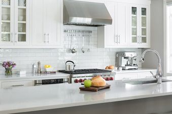 A modern kitchen at Pines Garden 4140 features white cabinets, subway tile backsplash, stainless steel appliances, and a large center island.
