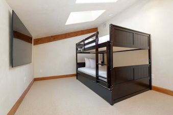 A cozy bunk bed setup in a room with light-colored walls, a skylight, and a mounted television, offering comfortable sleeping arrangements.