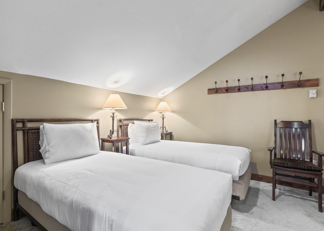 A bedroom with two twin beds and a chair.