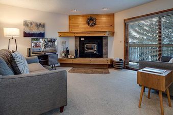 A cozy living room at Ranch at Steamboat RA411 with two gray sofas, a fireplace, and a large window with blinds.