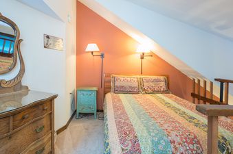 A charming bedroom at Manitou Lodge 8 features a cozy bed with a colorful quilt and rustic wooden furniture.