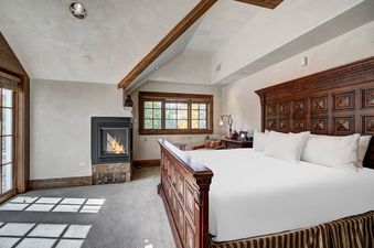 A cozy bedroom with a large bed, fireplace, and window offering an exterior view.