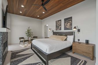 A bedroom with a king-sized bed, a fireplace, and a large window.