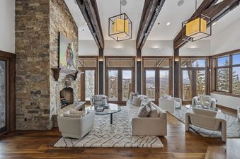 A spacious and inviting living room at Silver Horse at The Colony, featuring a stone fireplace, comfortable seating, and large windows with stunning mountain views.