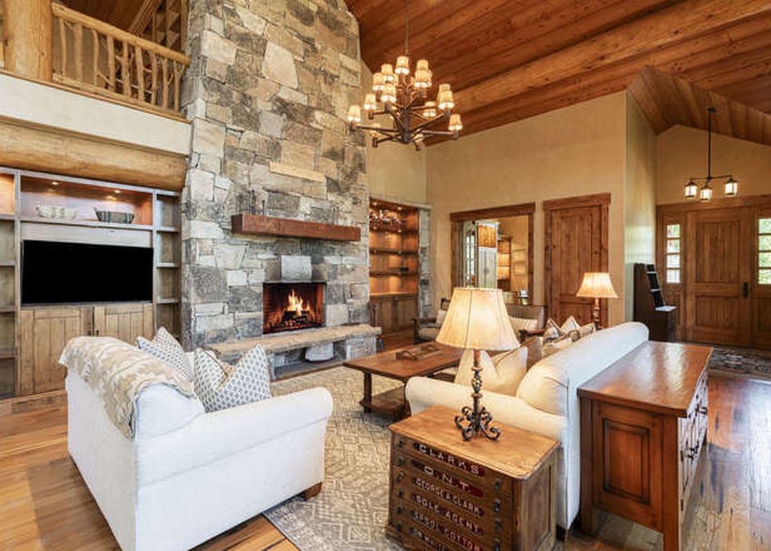 The living area of the Deer Valley Oak Lodge features a stone fireplace, comfortable sofas, and a rustic chandelier.