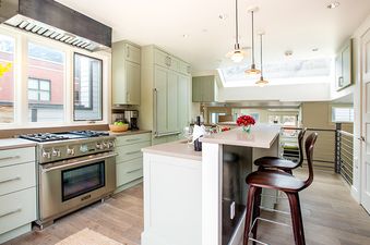 A modern kitchen with stainless steel appliances, a large island, and a skylight.