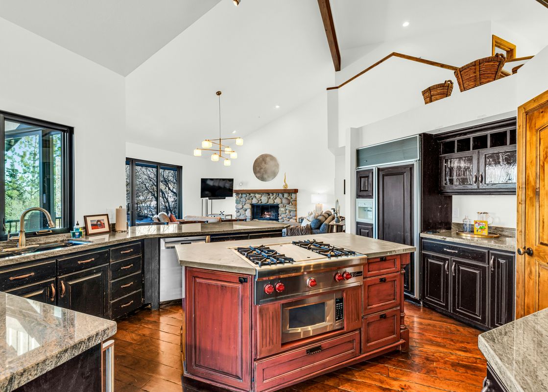 The kitchen in the Deer Valley Solamere Home has a large island with a cooktop and a sink near the window.