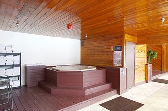 A large indoor hot tub with rich wooden paneling and ceiling, accompanied by a rack of neatly folded white towels.