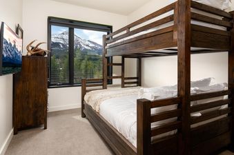 A bunk bed in the bedroom of Moonlight Basin 212 Lakelodge features a view of a snowy mountain peak in the distance.