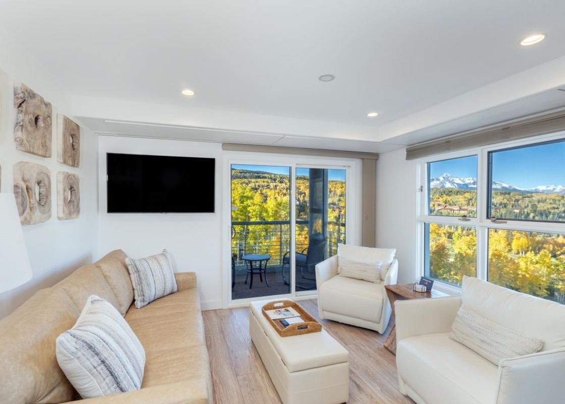 The Peaks Penthouse 434 offers breathtaking views of the mountains from its living area, with a comfortable couch and chairs situated to enjoy the scenery.