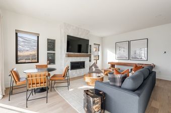 Modern living room at 1725 Amanti Lago featuring a grey sofa, fireplace, and dining table with a scenic view.