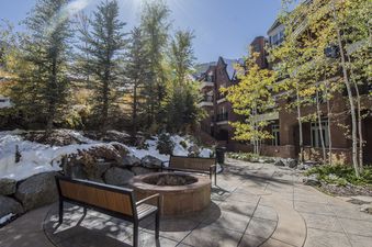 The exterior of the Hyatt Lodge Room building, featuring a fire pit area surrounded by snow, trees, and brick architecture.
