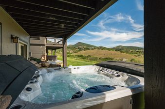 Outdoor hot tub under a covered patio at Mayflower Vista with scenic mountain views.