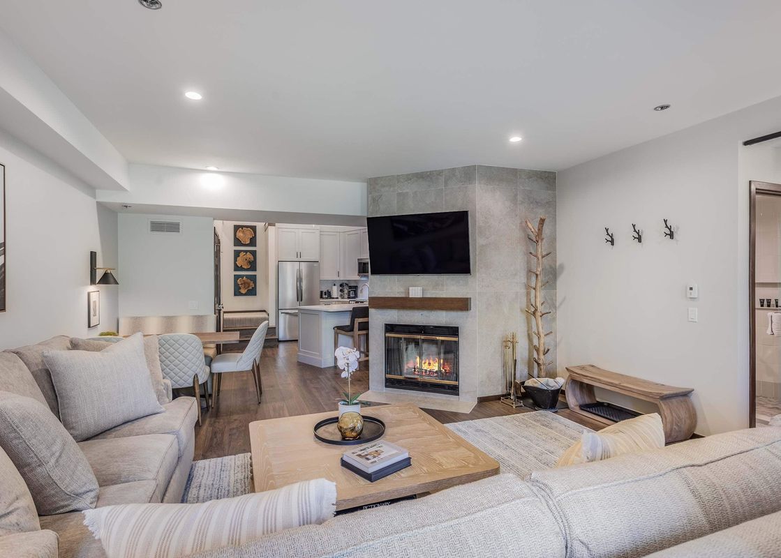 The open-concept living room and kitchen at Woodrun Place 40 feature comfortable sofas, a fireplace, a flat-screen TV, and a modern kitchen with a dining area.