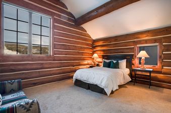 Cozy log cabin bedroom with a comfortable bed and scenic window views at Moose Drool Lodge.