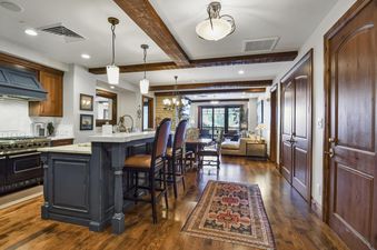 A view of the open-concept kitchen and living area at Silver Strike Lodge 201 203, featuring wood beams and polished hardwood flooring.