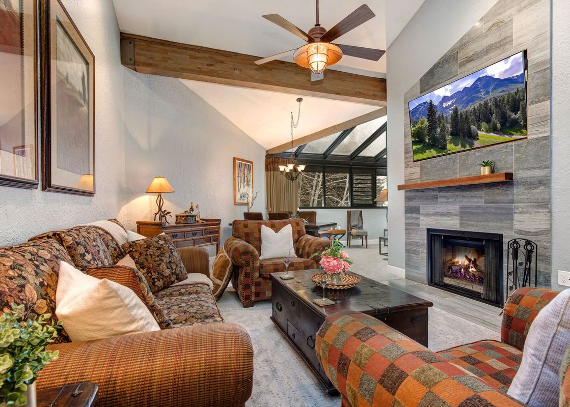 A cozy living room at Frostwood Links and Lodge with patterned furniture, a fireplace, and a large flat-screen TV.