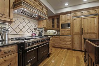 A fully equipped gourmet kitchen at Silver Strike Lodge 703 with natural wood cabinetry, granite countertops, a professional Viking range, and a copper sink.