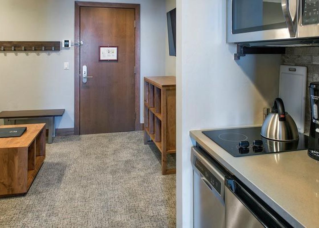 The living area within the Grand Colorado on Peak 8 Suite Residence features a modern kitchen, comfortable seating, and a view of the entry.