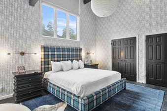 A contemporary bedroom featuring a blue plaid bedframe and patterned wallpaper at Twin Pines 6.