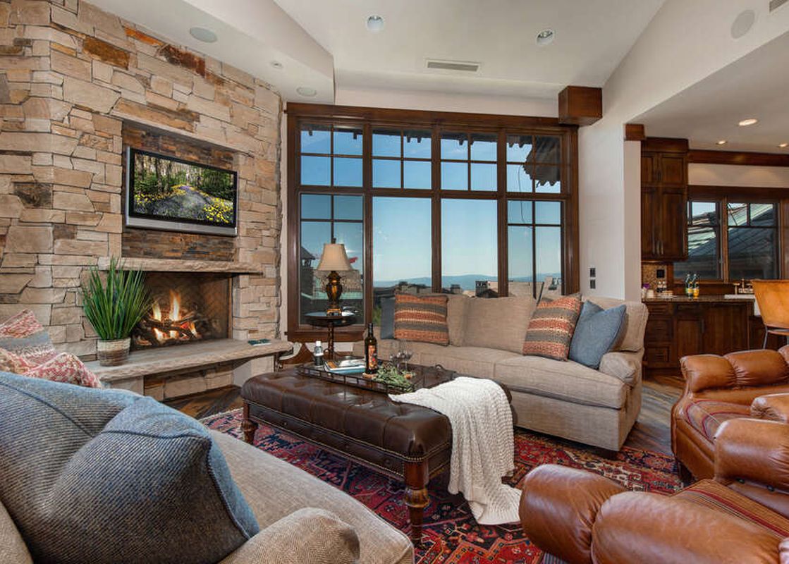 The Arrowleaf Overlook lounge area features a stone fireplace, large window, and comfortable seating.