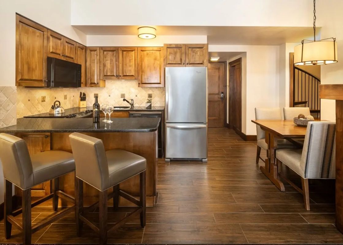 Kitchen and dining area of the Teton Mountain Lodge and Spa Sundance Junior Suite with wooden cabinetry and stainless steel appliances.