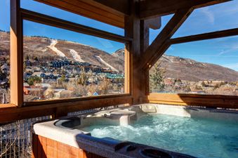 A private hot tub at Town Pointe C304 offers a view of snowy mountains and a town.