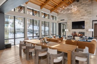 The dining area and living room of Lone Star Lodge Mountain Village with a large wooden table and comfortable seating, all illuminated by a unique chandelier.