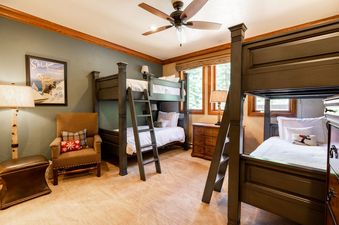 A bedroom with two bunk beds, a chair, and a dresser.