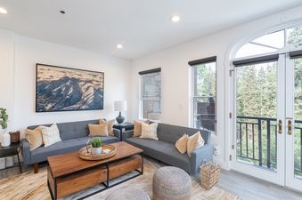 The living area is well-lit and features a comfortable seating arrangement and view of the forest.