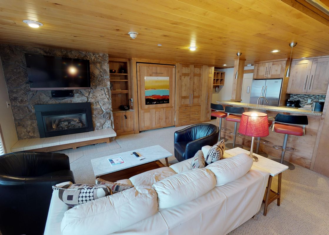 A living room with a fireplace, a large white couch, and a coffee table with a remote control on it.