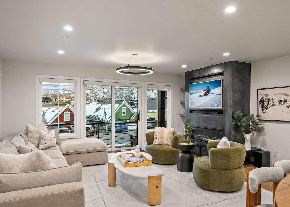 Modern and cozy living room at Bluebird Chalet Park City with a grey sectional, olive green armchairs, and a fireplace.