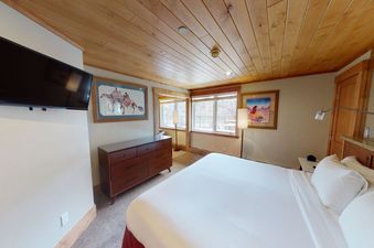 A bedroom with a large bed, a dresser, and a television.