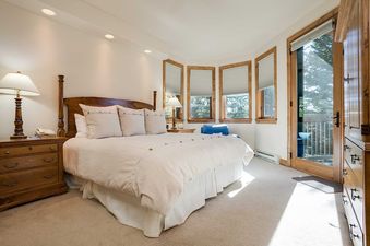 A bright and inviting bedroom with a king-sized bed, large windows with outdoor views, and access to a private balcony at Chateau Chamonix CX325.